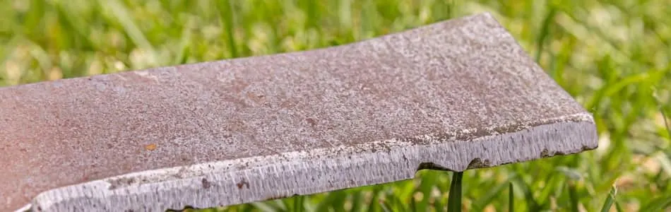 Dull lawn mower blade with gouges and chips in the mower blade