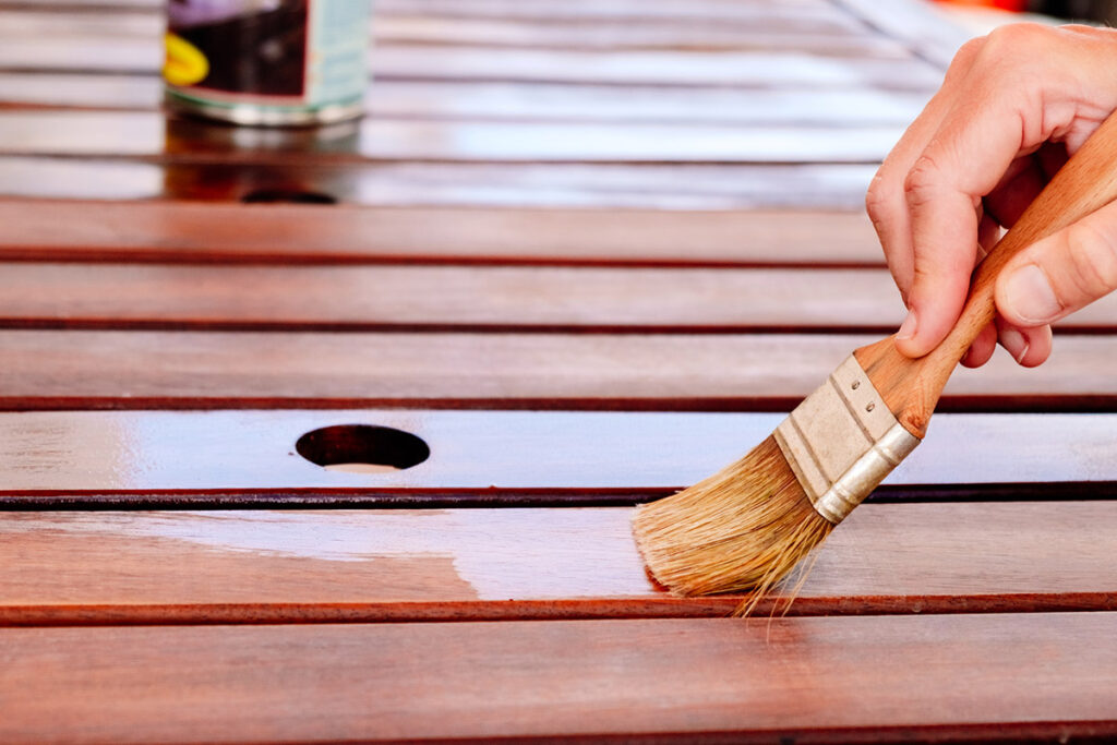 Apply teak oil on the boards of a wooden table to protect it fro