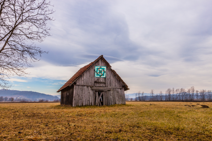 old barn in field during winter barn quilts
